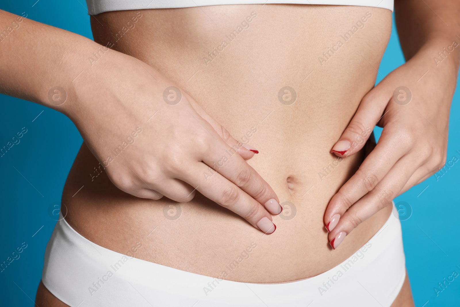 Photo of Young woman with flat belly on light blue background, closeup