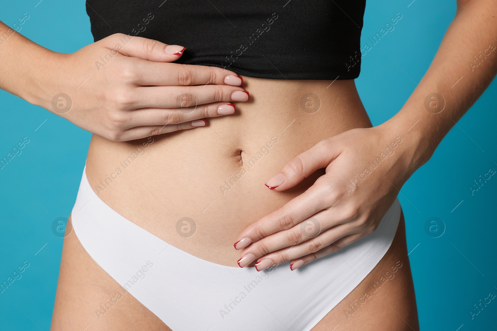 Photo of Young woman with flat belly on light blue background, closeup
