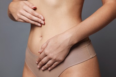 Photo of Young woman with flat belly on grey background, closeup