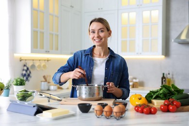 Photo of Smiling woman cooking at table in kitchen