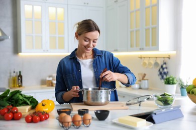 Photo of Smiling woman cooking at table in kitchen