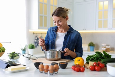 Photo of Smiling woman cooking at table in kitchen