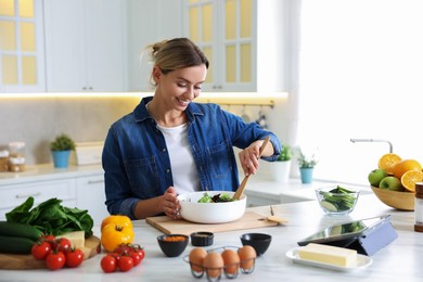 Photo of Smiling woman cooking at table in kitchen