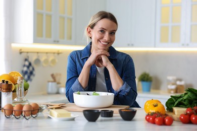 Photo of Portrait of smiling woman cooking at table in kitchen