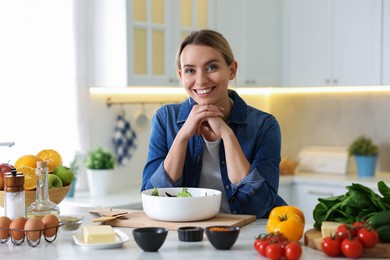 Photo of Portrait of smiling woman cooking at table in kitchen
