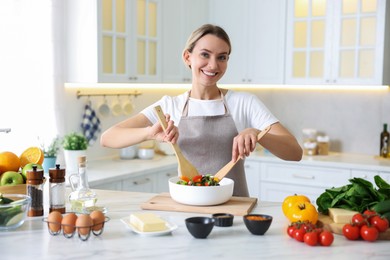 Photo of Portrait of smiling woman cooking at table in kitchen