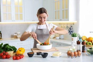 Photo of Smiling woman cooking at table in kitchen