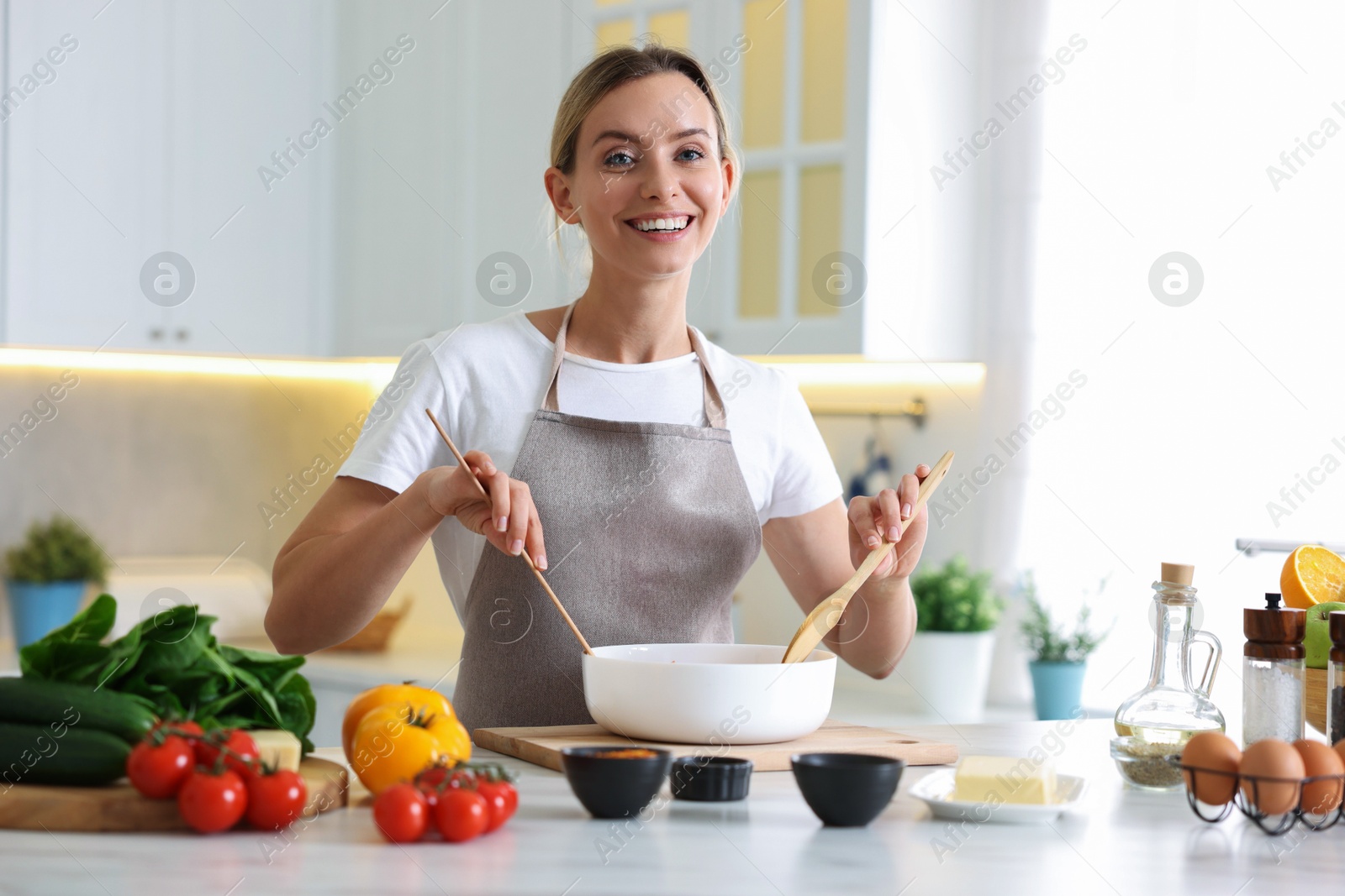 Photo of Portrait of smiling woman cooking at table in kitchen