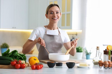Photo of Portrait of smiling woman cooking at table in kitchen