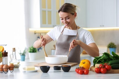 Photo of Smiling woman cooking at table in kitchen