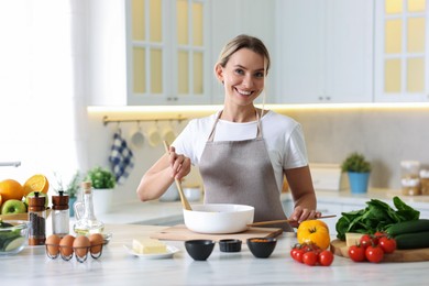 Photo of Portrait of smiling woman cooking at table in kitchen