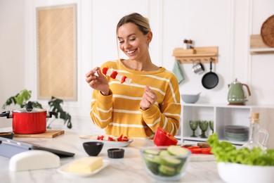 Photo of Smiling woman with tasty skewers after cooking at table in kitchen