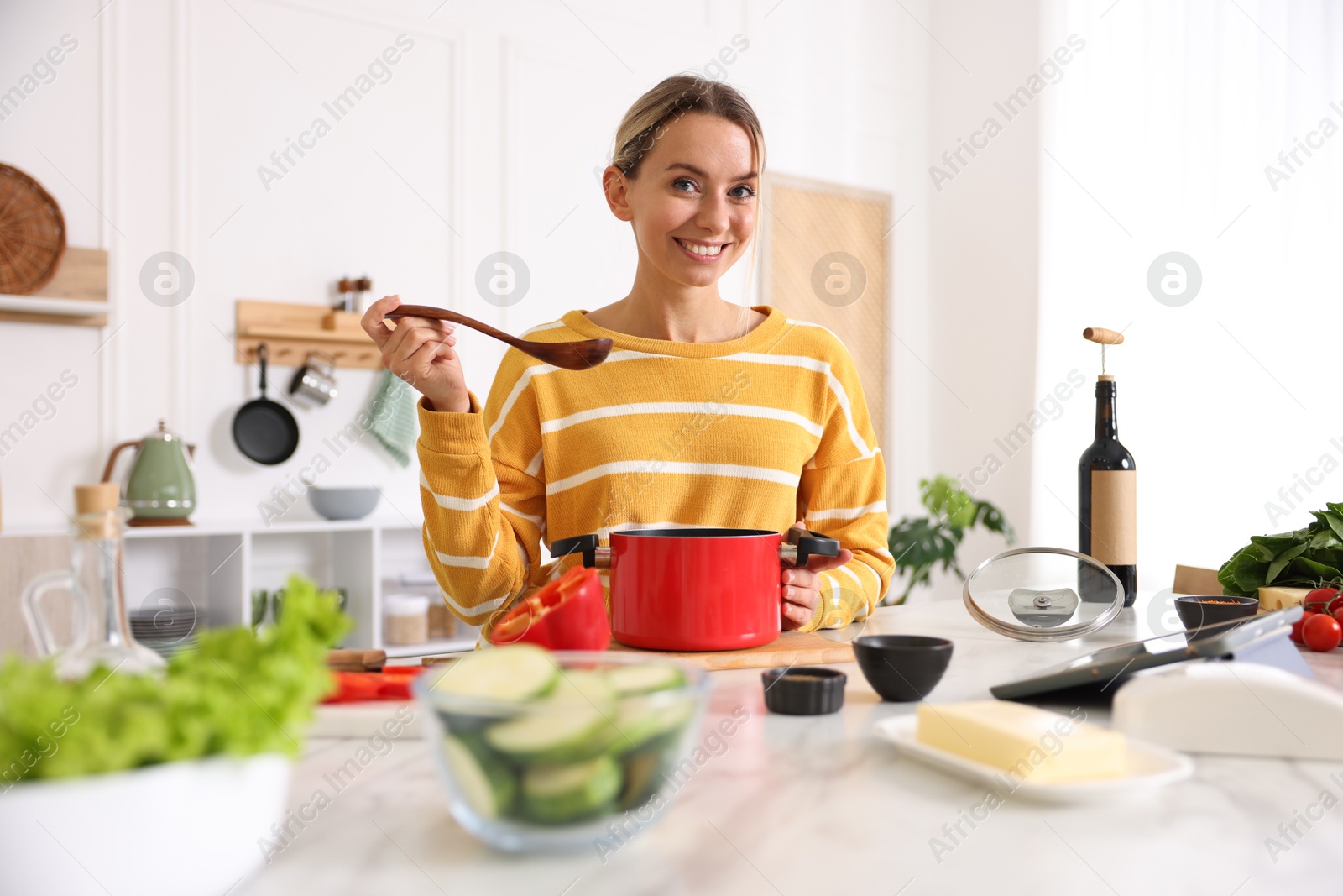 Photo of Smiling woman cooking at table in kitchen