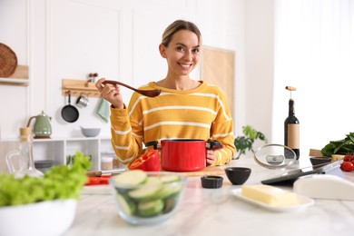 Photo of Smiling woman cooking at table in kitchen