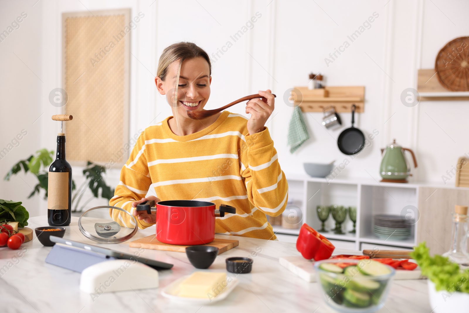 Photo of Smiling woman cooking at table in kitchen