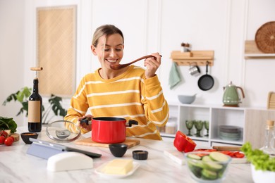 Photo of Smiling woman cooking at table in kitchen