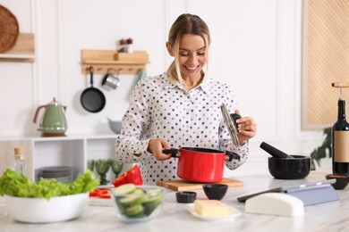 Photo of Smiling woman with pot cooking at table in kitchen