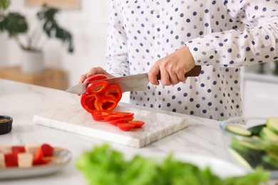 Photo of Cooking process. Woman cutting bell pepper at table indoors, closeup