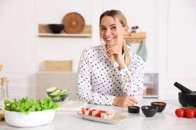 Photo of Portrait of smiling woman cooking at table in kitchen