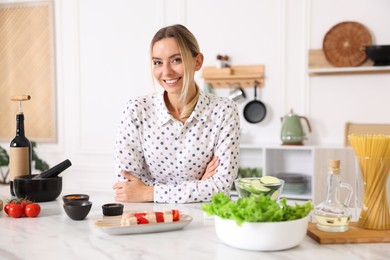 Photo of Portrait of smiling woman cooking at table in kitchen