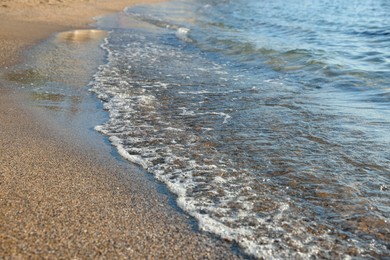 Photo of Beautiful wavy sea and sandy beach, closeup