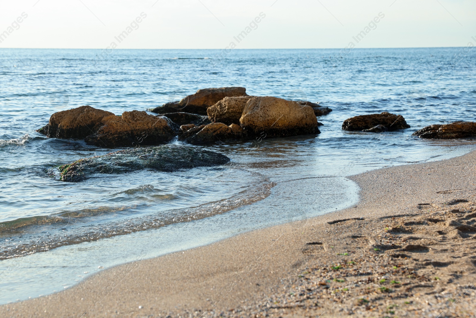 Photo of Beautiful wavy sea, stones and sandy beach