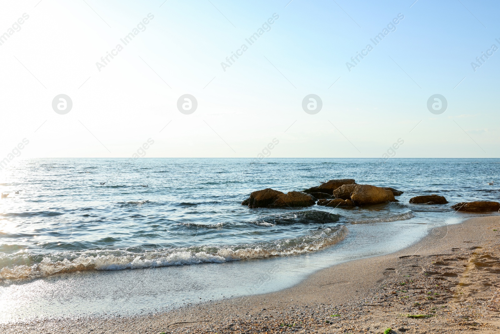 Beautiful wavy sea, stones and sandy beach Photo of Beautiful wavy sea, stones and sandy beach