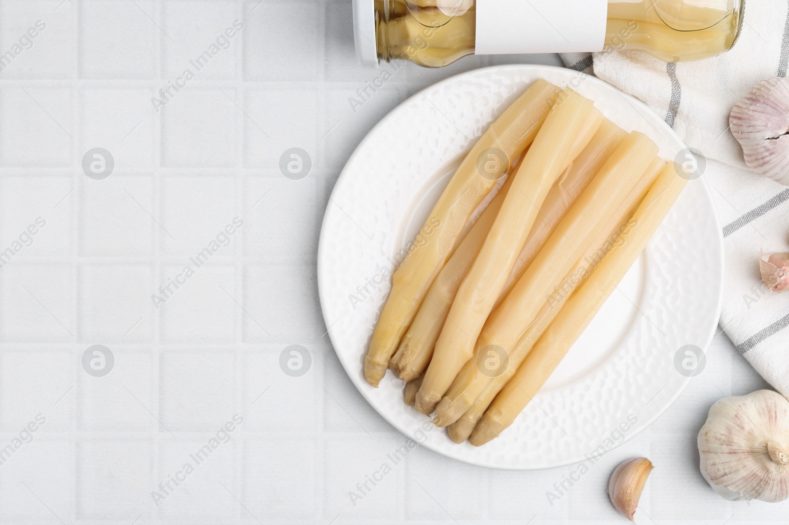 Pickled asparagus and garlic on white tiled table, flat lay. Space for text Photo of Pickled asparagus and garlic on white tiled table, flat lay. Space for text