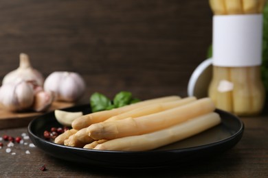 Photo of Pickled asparagus and spices on wooden table, closeup