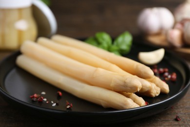 Photo of Pickled asparagus and spices on wooden table, closeup