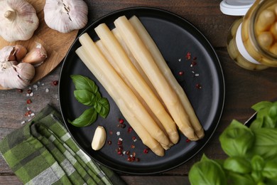 Photo of Pickled asparagus and spices on wooden table, flat lay