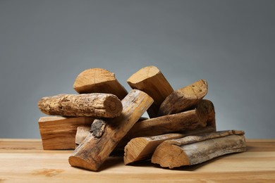 Photo of Pile of cut firewood on wooden table against grey background