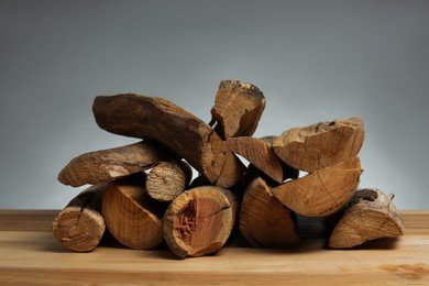 Photo of Pile of cut firewood on wooden table against grey background