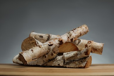 Photo of Pile of cut firewood on wooden table against grey background