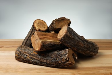Photo of Pile of cut firewood on wooden table against grey background, closeup