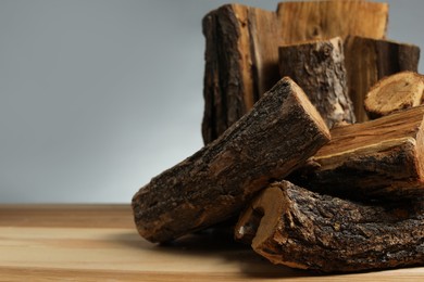 Photo of Pile of cut firewood on wooden table against grey background, closeup. Space for text