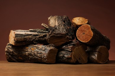 Photo of Pile of cut firewood on wooden table against brown background