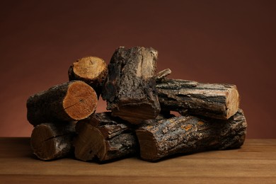 Photo of Pile of cut firewood on wooden table against brown background