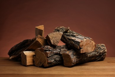 Photo of Pile of cut firewood on wooden table against brown background