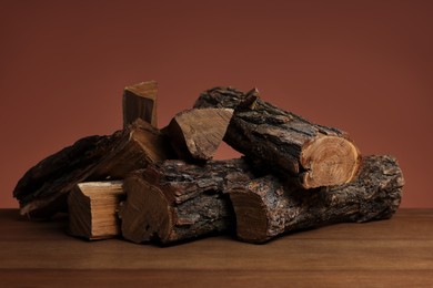 Photo of Pile of cut firewood on wooden table against brown background