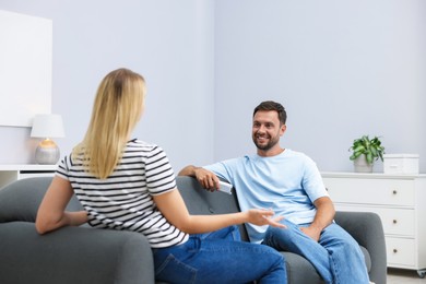 Photo of Couple with air conditioner remote control on sofa at home