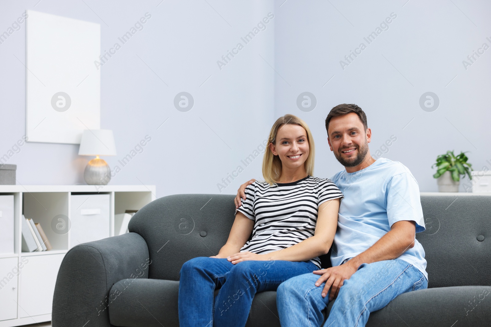 Photo of Happy couple spending time together on sofa at home. Space for text