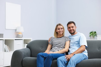 Photo of Happy couple spending time together on sofa at home. Space for text