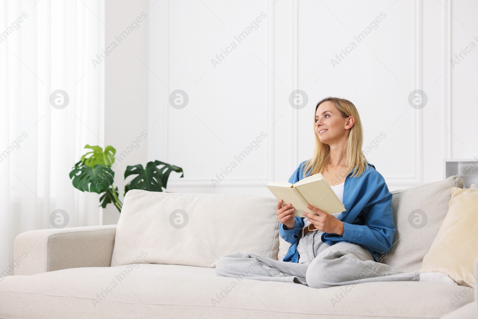 Woman reading book on sofa at home. Space for text Photo of Woman reading book on sofa at home. Space for text