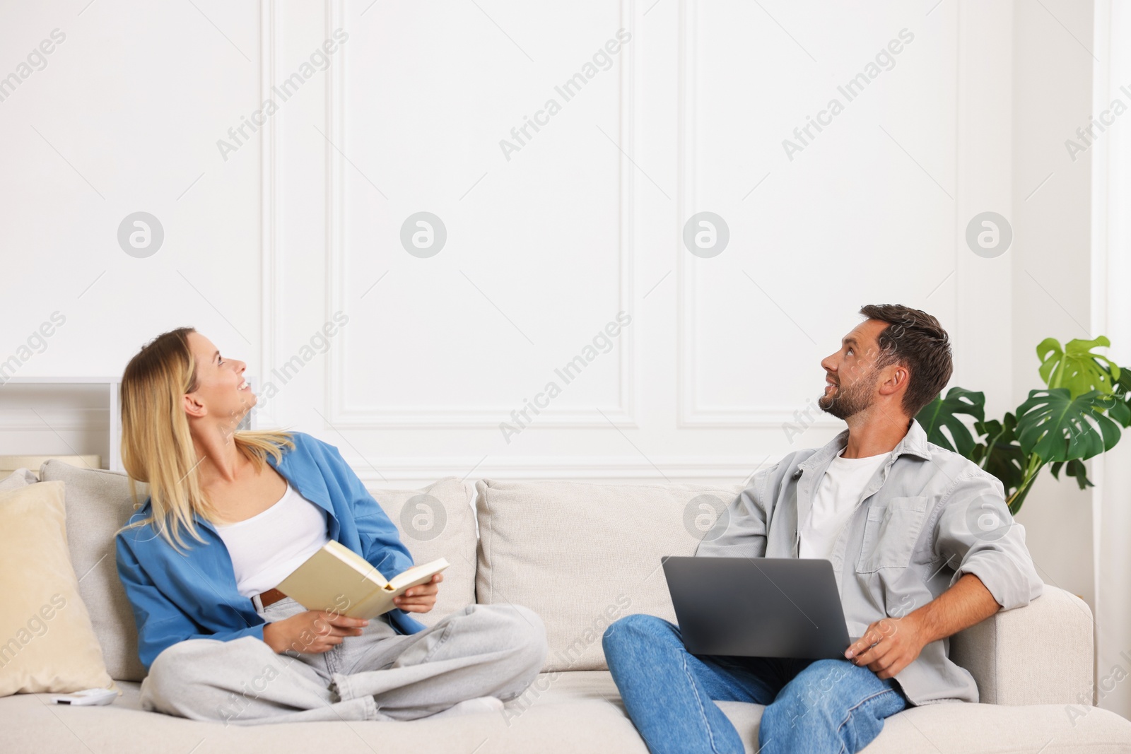 Photo of Happy couple spending time enjoying their hobbies on sofa at home
