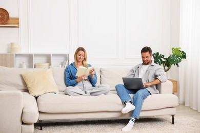 Photo of Happy couple spending time enjoying their hobbies on sofa at home