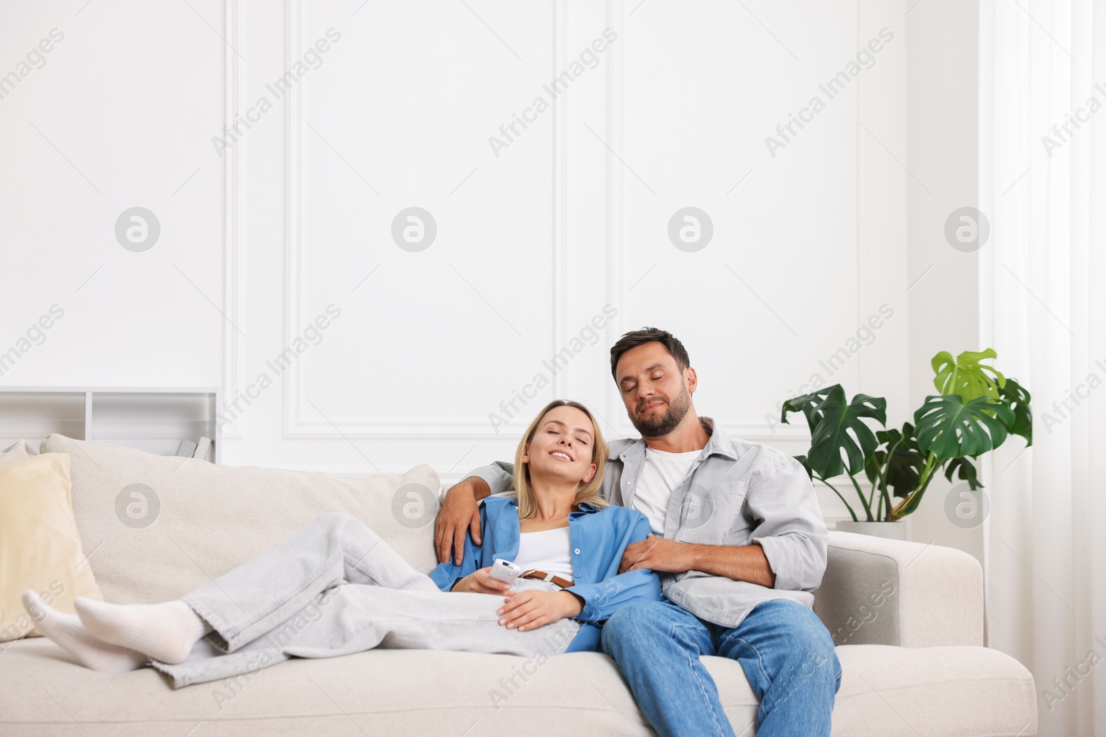 Photo of Happy couple spending time together on sofa at home. Space for text