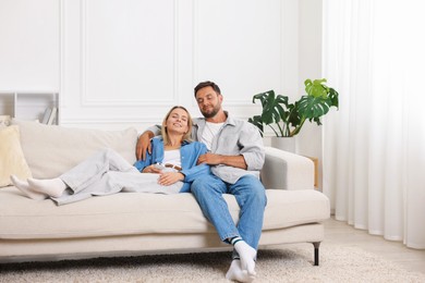 Photo of Happy couple spending time together on sofa at home