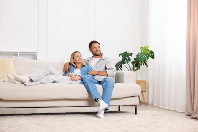 Photo of Happy couple spending time together on sofa at home