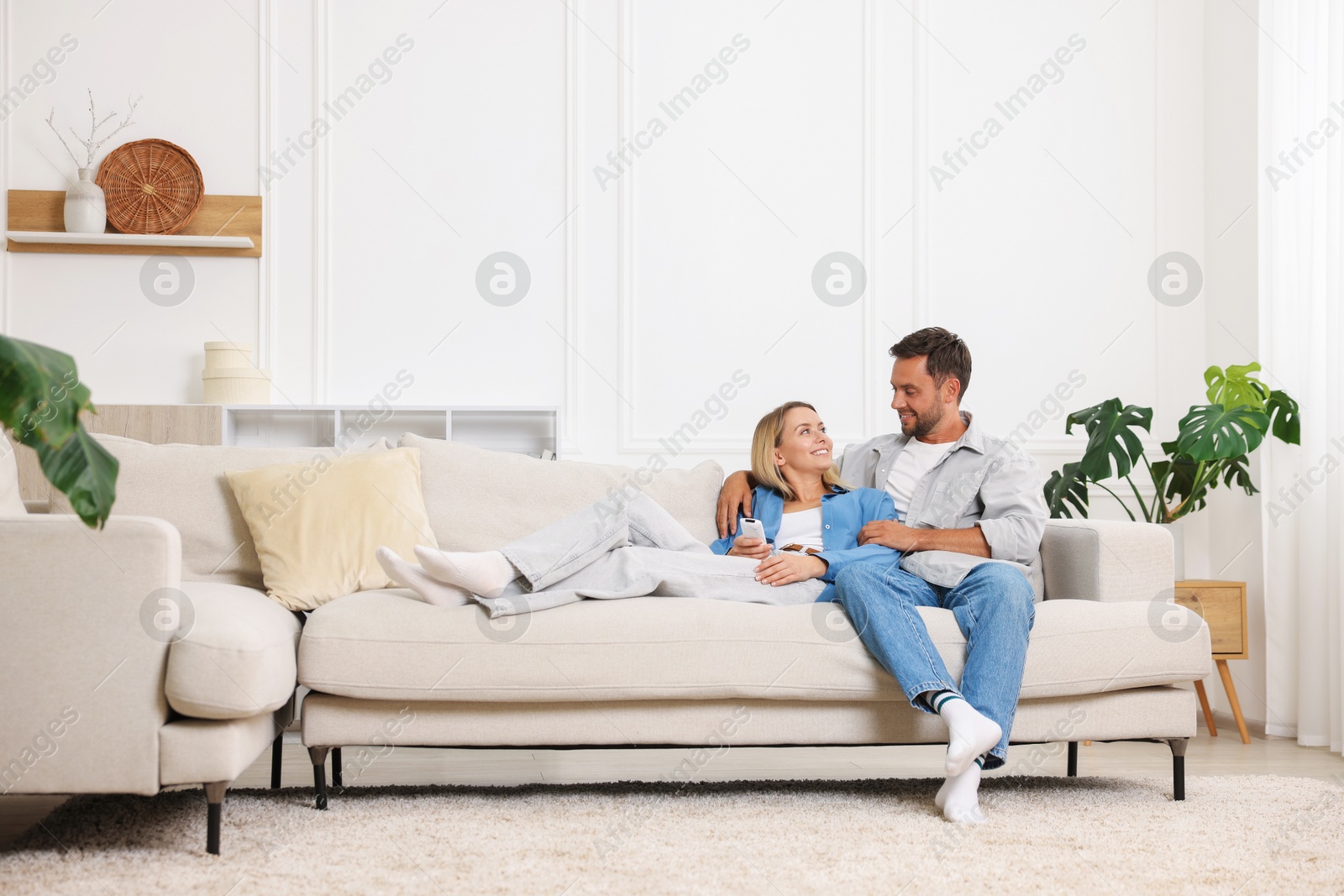 Photo of Happy couple spending time together on sofa at home. Space for text